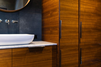 Inspiration for a large contemporary black tile and porcelain tile porcelain tile and gray floor bathroom remodel in Omaha with flat-panel cabinets, dark wood cabinets, a one-piece toilet, black walls, a vessel sink, marble countertops, a hinged shower door and white countertops