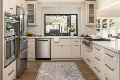Example of a small light wood floor eat-in kitchen design in Orange County with a drop-in sink, shaker cabinets, white cabinets, quartz countertops, white backsplash, porcelain backsplash, stainless steel appliances, no island and white countertops