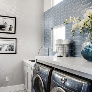 ロサンゼルスの中サイズのビーチスタイルのおしゃれな洗濯室 (アンダーカウンターシンク、シェーカースタイル扉のキャビネット、グレーのキャビネット、クオーツストーンカウンター、グレーの壁、磁器タイルの床、左右配置の洗濯機・乾燥機、グレーの床、白いキッチンカウンター) の写真