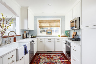 Example of a mid-sized transitional u-shaped dark wood floor and brown floor enclosed kitchen design in DC Metro with a farmhouse sink, shaker cabinets, white cabinets, quartz countertops, blue backsplash, ceramic backsplash, stainless steel appliances, no island and white countertops