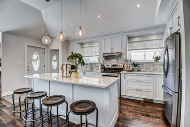 Open concept kitchen photo in Toronto with beaded inset cabinets, white cabinets, granite countertops, gray backsplash, brick backsplash, stainless steel appliances and an island