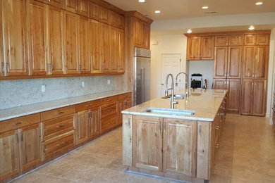 Example of a large l-shaped ceramic tile and multicolored floor kitchen design in Boise with raised-panel cabinets, medium tone wood cabinets, quartz countertops, multicolored backsplash, quartz backsplash, stainless steel appliances, an island and multicolored countertops