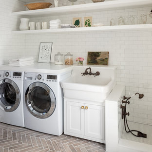 This is an example of a farmhouse single-wall utility room in Boston with a belfast sink, open cabinets, white cabinets, white walls, brick flooring, a side by side washer and dryer and white worktops.