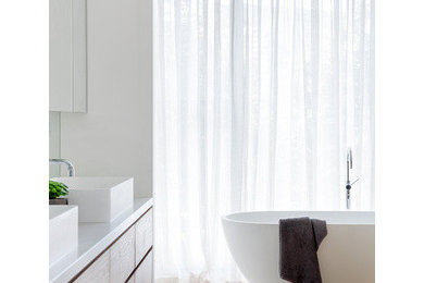 Inspiration for an expansive contemporary master wet room bathroom in Melbourne with furniture-like cabinets, medium wood cabinets, a freestanding tub, a one-piece toilet, limestone, beige walls, limestone floors, a vessel sink, engineered quartz benchtops, beige floor, an open shower and white benchtops.