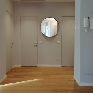 Exempel på en mellanstor modern hall, med grå väggar och ljust trägolv
