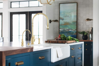 Design ideas for a mid-sized transitional galley eat-in kitchen in Grand Rapids with a farmhouse sink, shaker cabinets, blue cabinets, quartz benchtops, medium hardwood floors, with island and brown floor.