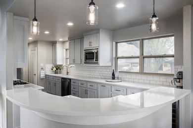Example of a mid-sized transitional galley dark wood floor and brown floor eat-in kitchen design in Dallas with an undermount sink, shaker cabinets, white cabinets, quartz countertops, white backsplash, subway tile backsplash, stainless steel appliances, a peninsula and white countertops