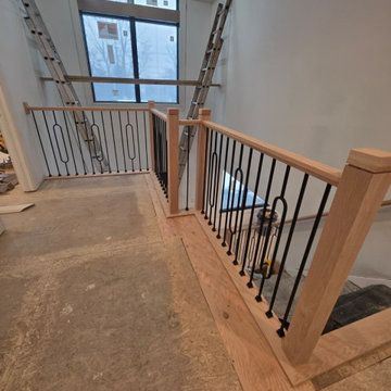 Stair Railing Installation Featuring Oval Metal Balusters and Red Oak Handrail