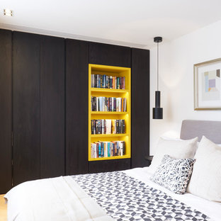 Imagen de dormitorio actual, de tamaño medio, sin chimenea, con paredes blancas, suelo de madera clara y suelo beige