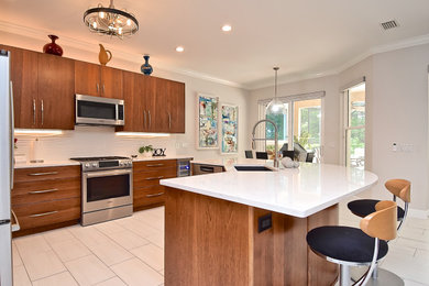Example of a mid-sized 1960s l-shaped ceramic tile and beige floor eat-in kitchen design in Tampa with an undermount sink, flat-panel cabinets, medium tone wood cabinets, quartz countertops, white backsplash, porcelain backsplash, stainless steel appliances, an island and white countertops