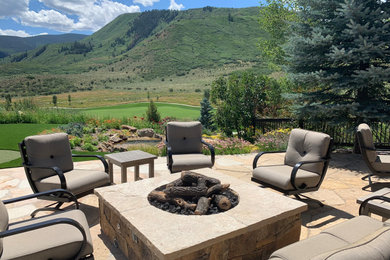 Inspiration for a mid-sized backyard stone patio remodel in Denver with a fire pit and no cover