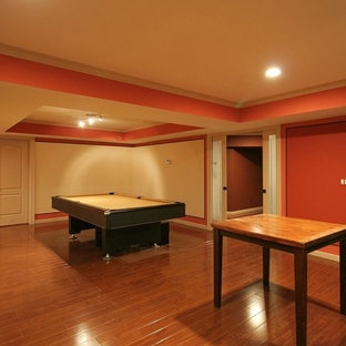 Inspiration for a medium sized traditional fully buried basement in Vancouver with orange walls, medium hardwood flooring, a standard fireplace, a stone fireplace surround and brown floors.