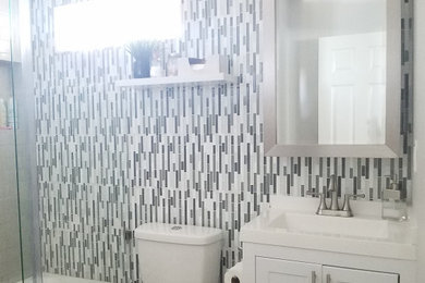 Example of a mid-sized beach style kids' gray tile and mosaic tile porcelain tile, gray floor and single-sink bathroom design in Los Angeles with recessed-panel cabinets, white cabinets, a two-piece toilet, beige walls, an integrated sink, marble countertops, white countertops and a freestanding vanity