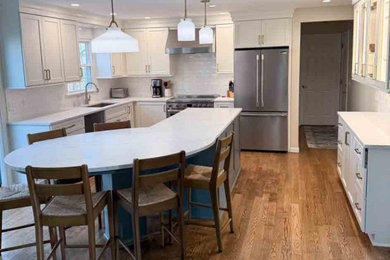 Kitchen - traditional medium tone wood floor and brown floor kitchen idea in Cleveland with an undermount sink, shaker cabinets, white cabinets, quartz countertops, white backsplash, stainless steel appliances, an island and white countertops