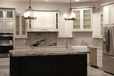 Large transitional l-shaped light wood floor eat-in kitchen photo in Phoenix with a farmhouse sink, raised-panel cabinets, white cabinets, marble countertops, white backsplash, ceramic backsplash, stainless steel appliances and an island