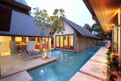 Inspiration for a large modern courtyard custom-shaped lap pool in Cairns with a pool house and stamped concrete.