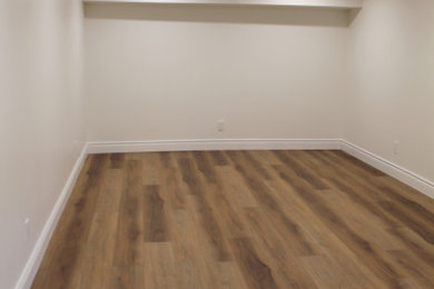 Mid-sized look-out laminate floor and brown floor basement photo in Other with white walls