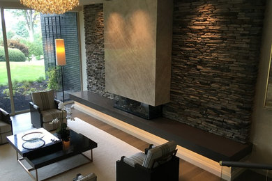 Стильный дизайн: гостиная комната с фасадом камина из камня - последний тренд