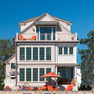 ニューヨークのビーチスタイルのおしゃれな家の外観 (木材サイディング、ピンクの外壁) の写真