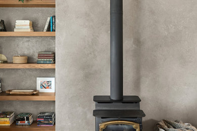 Large danish enclosed light wood floor and brown floor living room library photo in Sacramento with gray walls, a wood stove and a plaster fireplace