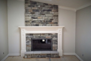 Family room in Cleveland with a standard fireplace, a stone fireplace surround, grey walls and carpet.