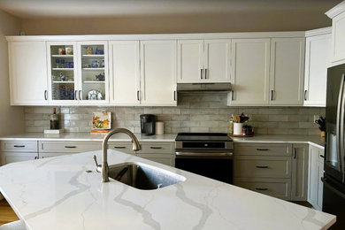Inspiration for a mid-sized transitional l-shaped medium tone wood floor and brown floor eat-in kitchen remodel in Other with an undermount sink, shaker cabinets, white cabinets, quartz countertops, gray backsplash, subway tile backsplash, stainless steel appliances, an island and white countertops