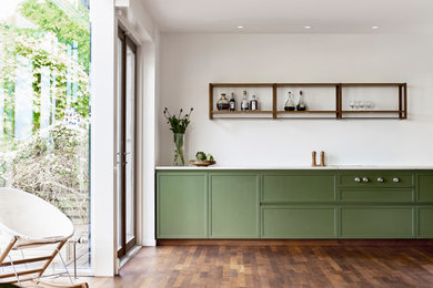 This is an example of a mid-sized transitional galley open plan kitchen in Copenhagen with green cabinets, marble benchtops, with island, brown floor and white benchtop.