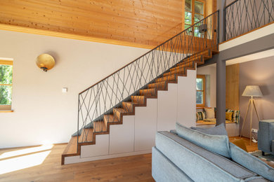 Imagen de escalera contemporánea con escalones de madera, contrahuellas de madera y barandilla de metal