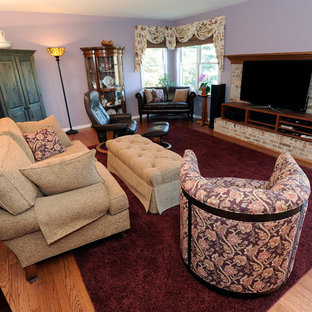 Ejemplo de salón cerrado, mediterráneo, grande, con paredes púrpuras, suelo de madera en tonos medios, chimenea tradicional y marco de chimenea de ladrillo