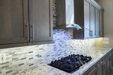 Example of a mid-sized transitional u-shaped laminate floor and beige floor eat-in kitchen design in Phoenix with a drop-in sink, shaker cabinets, medium tone wood cabinets, granite countertops, beige backsplash, glass sheet backsplash, stainless steel appliances, a peninsula and beige countertops