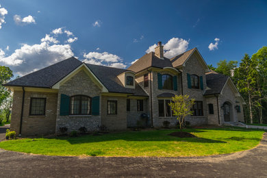 Example of a large classic beige three-story stone exterior home design in Other with a shingle roof