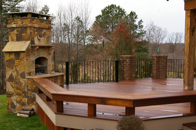 This is an example of a large country backyard deck in Charlotte with a fire feature and a roof extension.