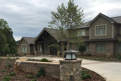Large elegant three-story brick exterior home photo in Other with a metal roof