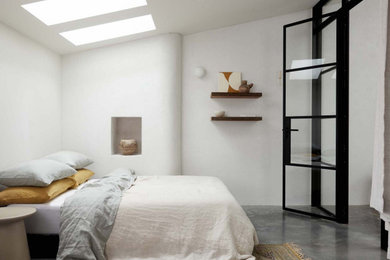 Aménagement d'une chambre mansardée ou avec mezzanine contemporaine de taille moyenne avec un mur blanc, sol en béton ciré et un sol gris.