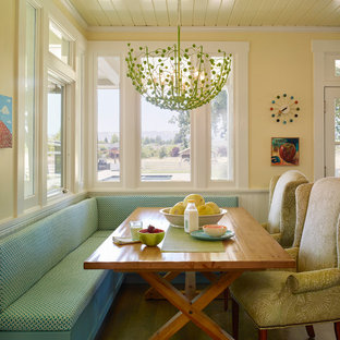Aménagement d'une salle à manger campagne avec un mur jaune et un sol en bois foncé.