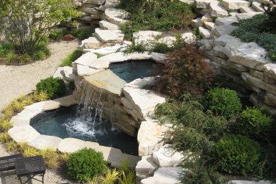 This is an example of a mid-sized contemporary backyard garden in Chicago with a water feature and natural stone pavers.