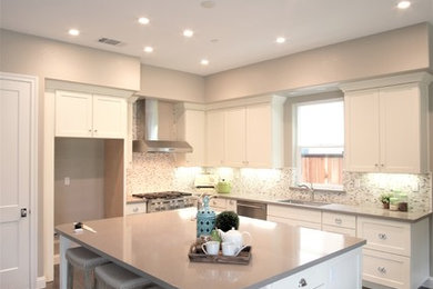 Inspiration for a large traditional l-shaped eat-in kitchen in San Francisco with an undermount sink, shaker cabinets, white cabinets, quartz benchtops, beige splashback, porcelain splashback, stainless steel appliances, laminate floors and brown floor.