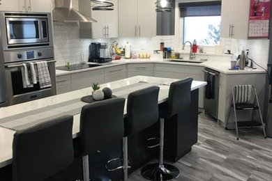 Inspiration for a modern vinyl floor and gray floor kitchen remodel in Other with white cabinets, marble countertops, white backsplash, glass tile backsplash, stainless steel appliances, an island and white countertops