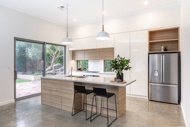 Mid-sized contemporary galley kitchen pantry in Adelaide with an undermount sink, flat-panel cabinets, light wood cabinets, quartz benchtops, white splashback, subway tile splashback, stainless steel appliances, concrete floors, with island, grey floor and grey benchtop.