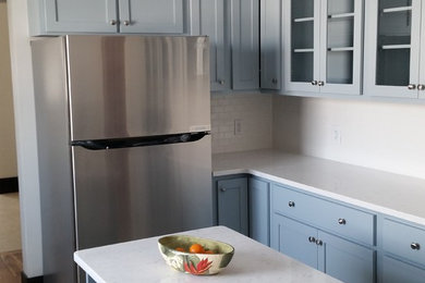 Kitchen - mid-sized country u-shaped concrete floor kitchen idea in Denver with shaker cabinets, blue cabinets, quartzite countertops, white backsplash, subway tile backsplash, stainless steel appliances and an island