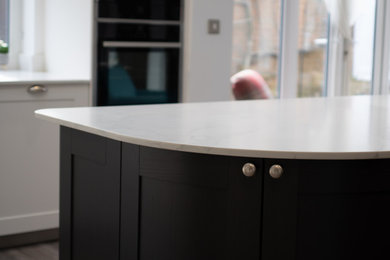 This is an example of a classic kitchen in Other with shaker cabinets, black cabinets, white splashback, stone slab splashback and white worktops.