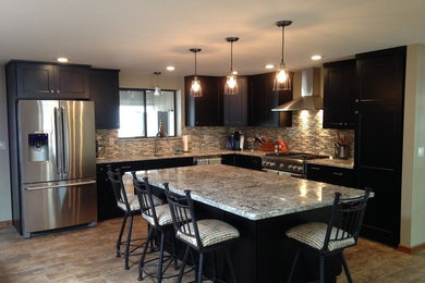 Example of a mid-sized southwest l-shaped limestone floor and beige floor eat-in kitchen design in Phoenix with a double-bowl sink, shaker cabinets, dark wood cabinets, granite countertops, multicolored backsplash, glass tile backsplash, stainless steel appliances and an island