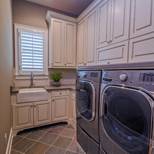 アトランタの中サイズのトランジショナルスタイルのおしゃれなランドリールーム (エプロンフロントシンク、レイズドパネル扉のキャビネット、ベージュのキャビネット、茶色い壁、磁器タイルの床、左右配置の洗濯機・乾燥機) の写真