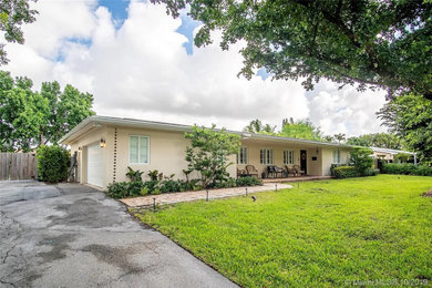 Mid-sized elegant beige one-story stucco house exterior photo with a hip roof, a tile roof and a brown roof
