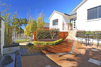 This is an example of a small tropical front yard full sun formal garden for summer in Sydney with a garden path and decking.