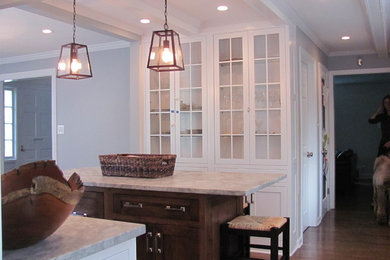 Mid-sized transitional medium tone wood floor kitchen photo in New York with an undermount sink, beaded inset cabinets, white cabinets, marble countertops, white backsplash, stainless steel appliances and an island