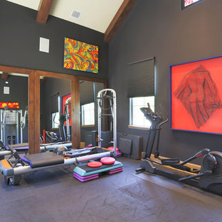 Modern inredning av ett hemmagym med grovkök, med svarta väggar och grått golv