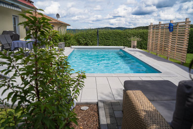 Moderner Pool neben dem Haus in rechteckiger Form mit Natursteinplatten in Sonstige