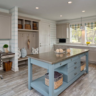 ミネアポリスの大きいビーチスタイルのおしゃれな家事室 (アンダーカウンターシンク、フラットパネル扉のキャビネット、白いキャビネット、クオーツストーンカウンター、グレーの壁、ラミネートの床、左右配置の洗濯機・乾燥機、茶色い床、グレーのキッチンカウンター) の写真