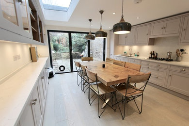 Design ideas for a medium sized contemporary single-wall kitchen/diner in London with a built-in sink, shaker cabinets, purple cabinets, composite countertops, white splashback, stainless steel appliances, medium hardwood flooring, no island, brown floors and white worktops.